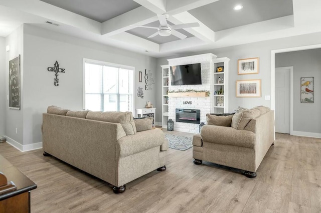 living area featuring visible vents, coffered ceiling, baseboards, light wood-style flooring, and a fireplace