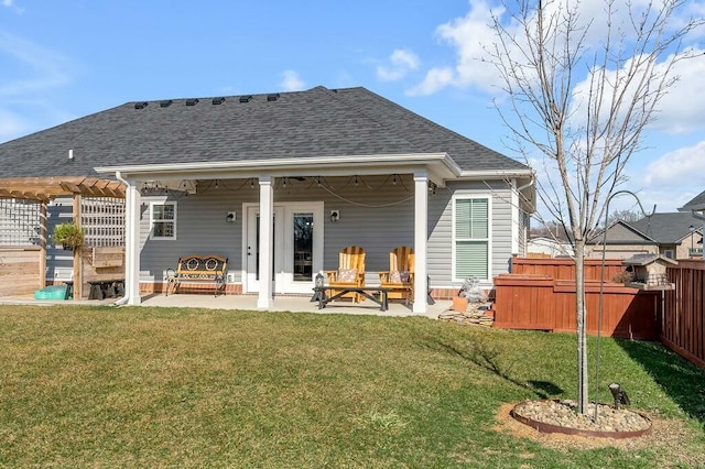 rear view of property with a shingled roof, fence, a lawn, a patio area, and a pergola