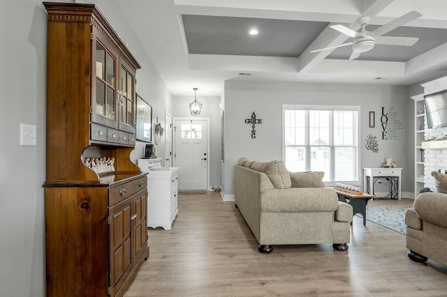 living area featuring a ceiling fan, baseboards, coffered ceiling, beam ceiling, and light wood-style flooring