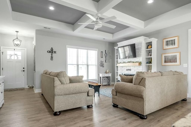 living area featuring light wood-type flooring, coffered ceiling, visible vents, and ceiling fan