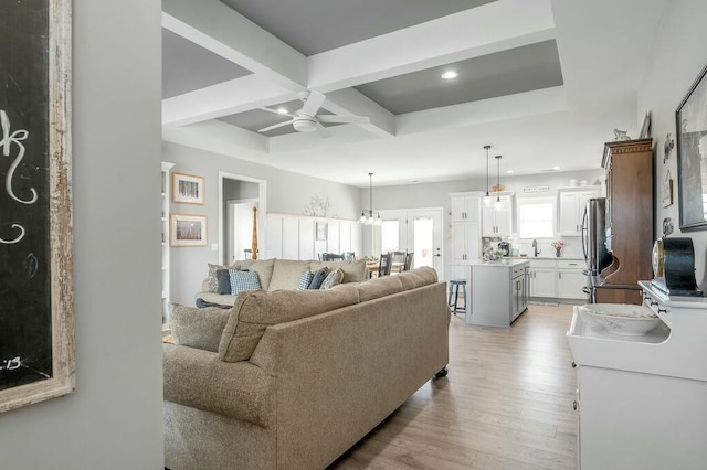 living room with light wood finished floors, beam ceiling, recessed lighting, coffered ceiling, and a ceiling fan