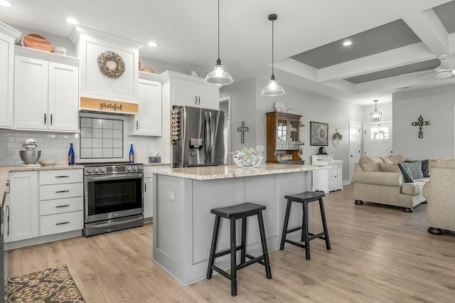 kitchen featuring light wood-style flooring, stainless steel appliances, open floor plan, a kitchen bar, and tasteful backsplash