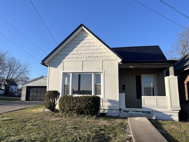 view of front of property featuring an outbuilding, a standing seam roof, a porch, aphalt driveway, and metal roof