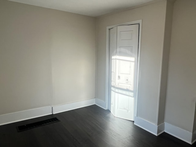 spare room with dark wood finished floors, visible vents, and baseboards