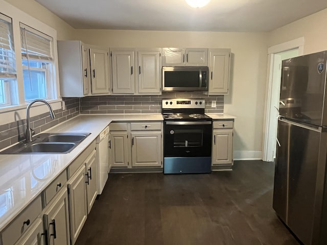 kitchen with dark wood-style flooring, a sink, decorative backsplash, light countertops, and appliances with stainless steel finishes