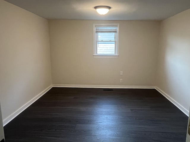 unfurnished room with baseboards and dark wood-style flooring