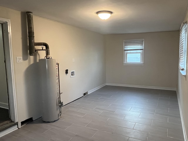 clothes washing area with baseboards, laundry area, and water heater