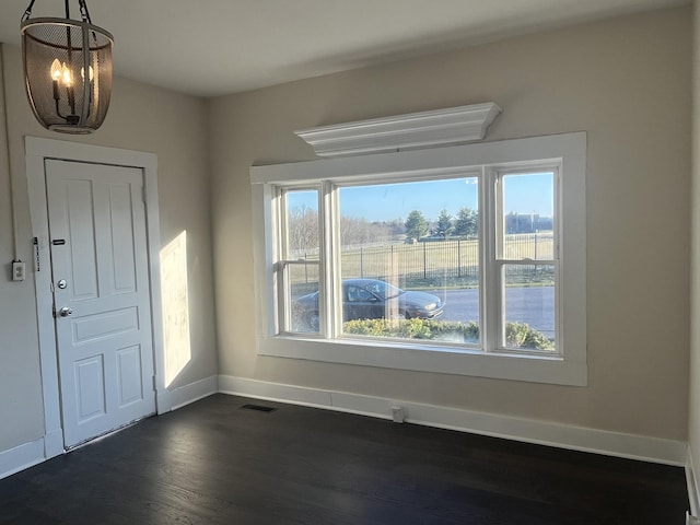 foyer with visible vents, dark wood-style floors, baseboards, and a chandelier