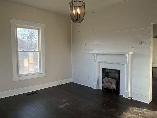 unfurnished living room featuring visible vents, dark wood-type flooring, baseboards, a chandelier, and a fireplace