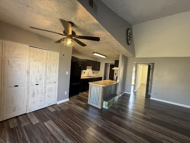 kitchen with visible vents, dark wood-style flooring, freestanding refrigerator, a sink, and light countertops