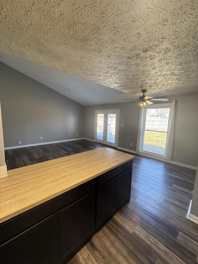 empty room with a wealth of natural light, baseboards, and dark wood-style flooring