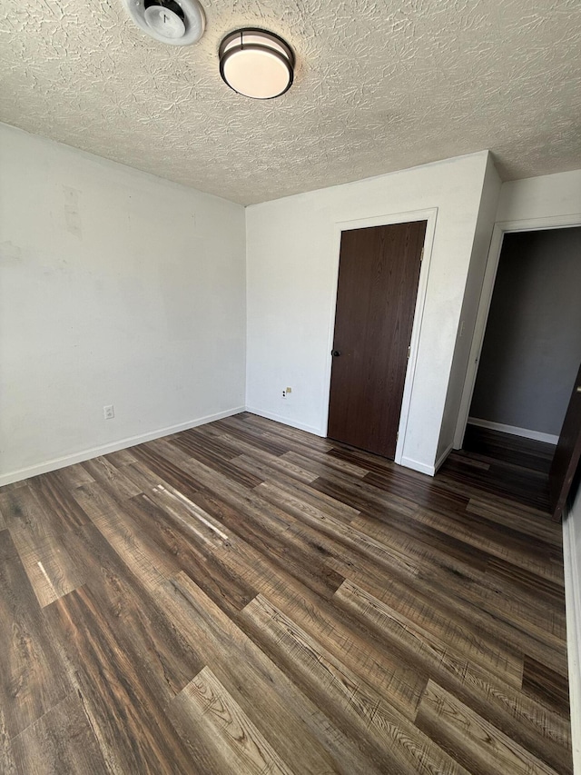 unfurnished bedroom with dark wood-style floors, baseboards, a closet, and a textured ceiling