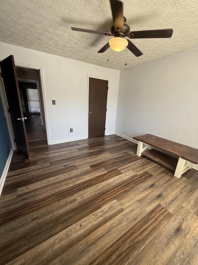 unfurnished bedroom featuring dark wood-type flooring, a ceiling fan, baseboards, and a textured ceiling