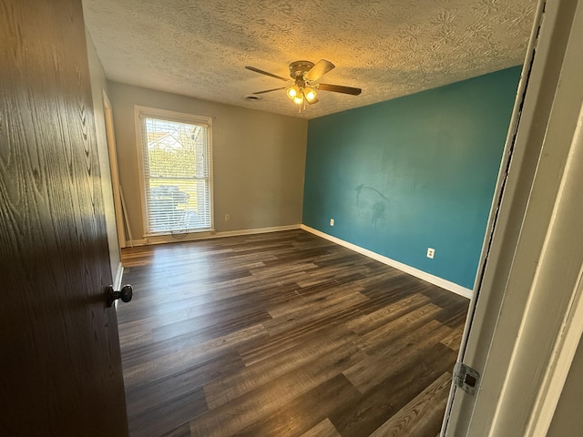 spare room with a textured ceiling, a ceiling fan, baseboards, and dark wood-style flooring