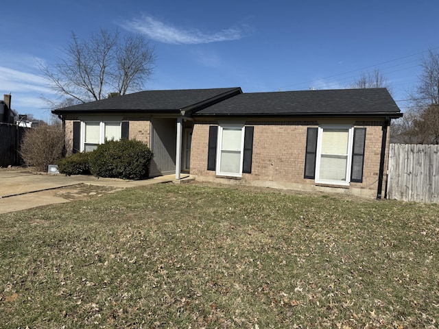 ranch-style home with brick siding, a shingled roof, a front lawn, and fence