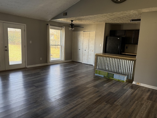 unfurnished living room with visible vents, baseboards, lofted ceiling, a textured ceiling, and dark wood-style flooring