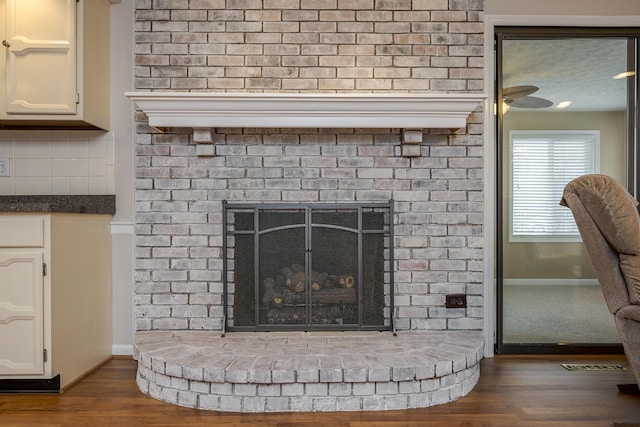 details featuring visible vents, backsplash, baseboards, a fireplace, and wood finished floors