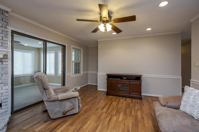 living area with baseboards, wood finished floors, and ornamental molding