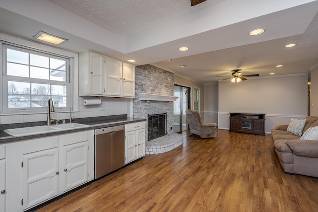 kitchen with a wealth of natural light, a sink, dark countertops, open floor plan, and dishwasher