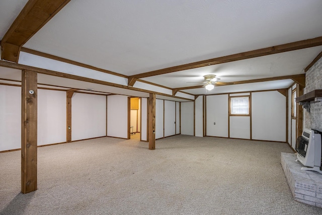 unfurnished living room with beamed ceiling, light carpet, a ceiling fan, heating unit, and a fireplace