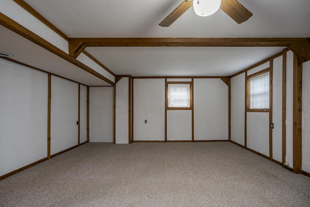 unfurnished room with beamed ceiling, light colored carpet, and a ceiling fan