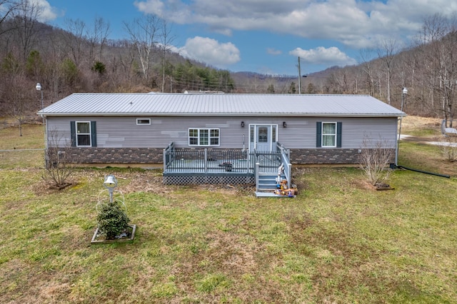 view of front facade featuring a forest view, a wooden deck, metal roof, and a front yard