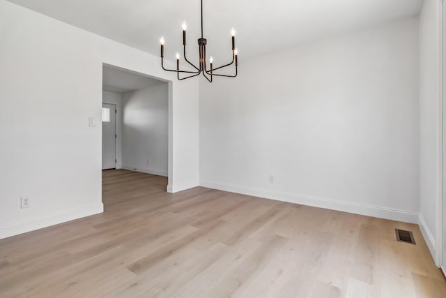 unfurnished dining area featuring a notable chandelier, light wood-style floors, visible vents, and baseboards