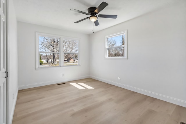 unfurnished room featuring light wood finished floors, visible vents, and baseboards