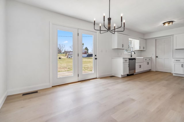 kitchen with light wood-style floors, plenty of natural light, stainless steel dishwasher, and light countertops