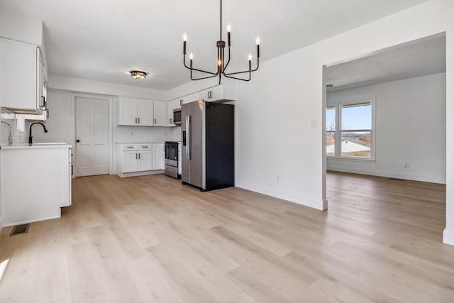 kitchen featuring visible vents, a sink, stainless steel appliances, light countertops, and light wood-type flooring