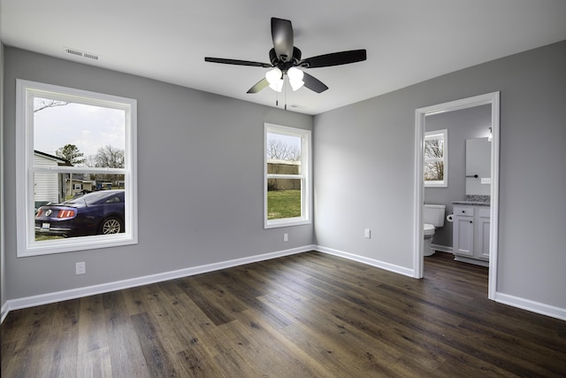 unfurnished bedroom featuring dark wood finished floors, multiple windows, baseboards, and visible vents