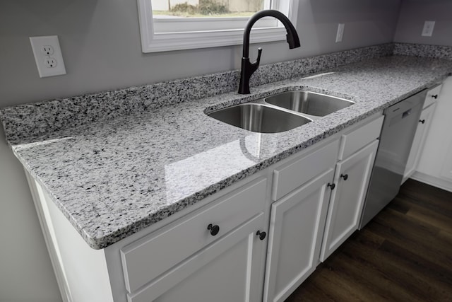 kitchen featuring light stone countertops, dark wood-style floors, white cabinetry, a sink, and stainless steel dishwasher