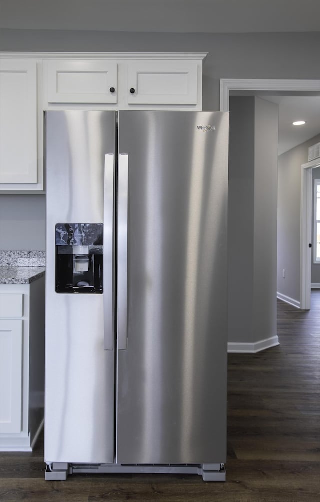 details with light stone counters, dark wood finished floors, white cabinets, and stainless steel fridge with ice dispenser