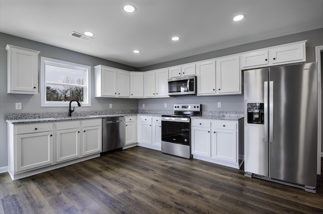 kitchen with dark wood-style floors, visible vents, a sink, stainless steel appliances, and white cabinets