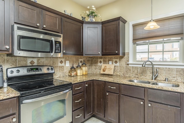 kitchen featuring a sink, light stone counters, tasteful backsplash, stainless steel appliances, and dark brown cabinets