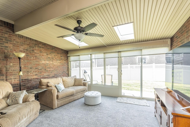 living room featuring a skylight, carpet, brick wall, and ceiling fan