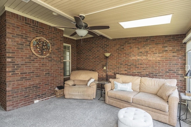 unfurnished living room featuring a ceiling fan, brick wall, and carpet floors