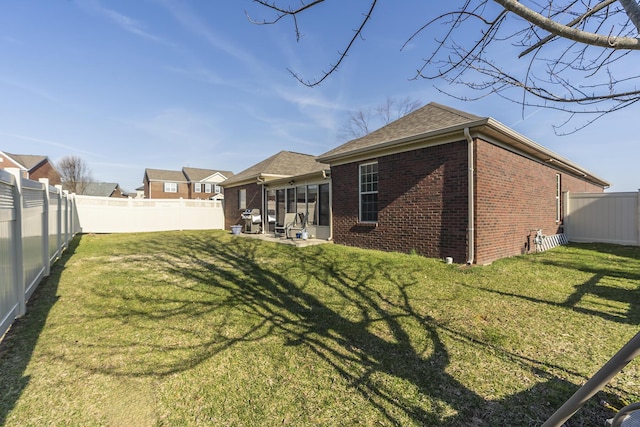 rear view of house featuring brick siding, a patio area, a lawn, and a fenced backyard