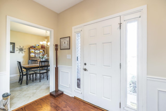 foyer with an inviting chandelier, dark wood-style floors, and wainscoting