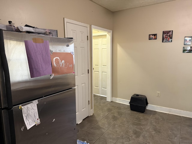 interior space featuring dark tile patterned flooring, baseboards, and freestanding refrigerator