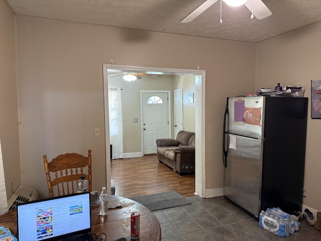 interior space featuring baseboards, a textured ceiling, ceiling fan, and dark tile patterned flooring