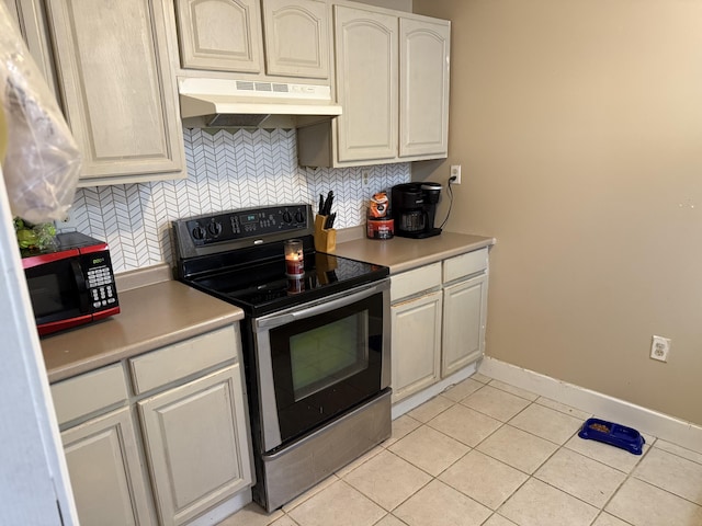 kitchen with under cabinet range hood, light tile patterned floors, backsplash, and electric stove