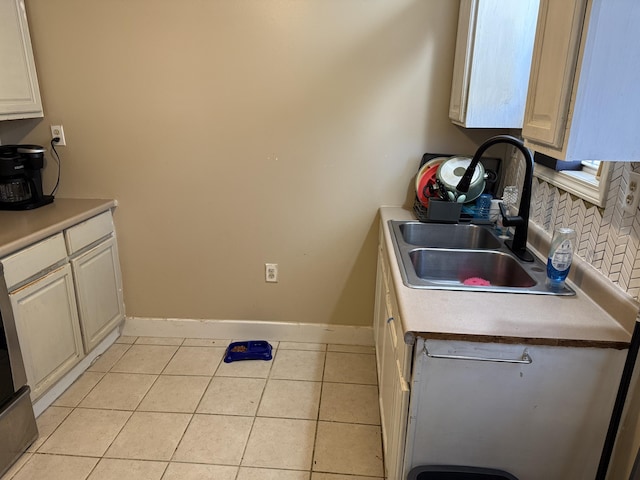 kitchen featuring light countertops, light tile patterned floors, baseboards, and a sink