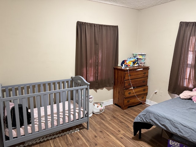 bedroom with wood finished floors, baseboards, and a textured ceiling