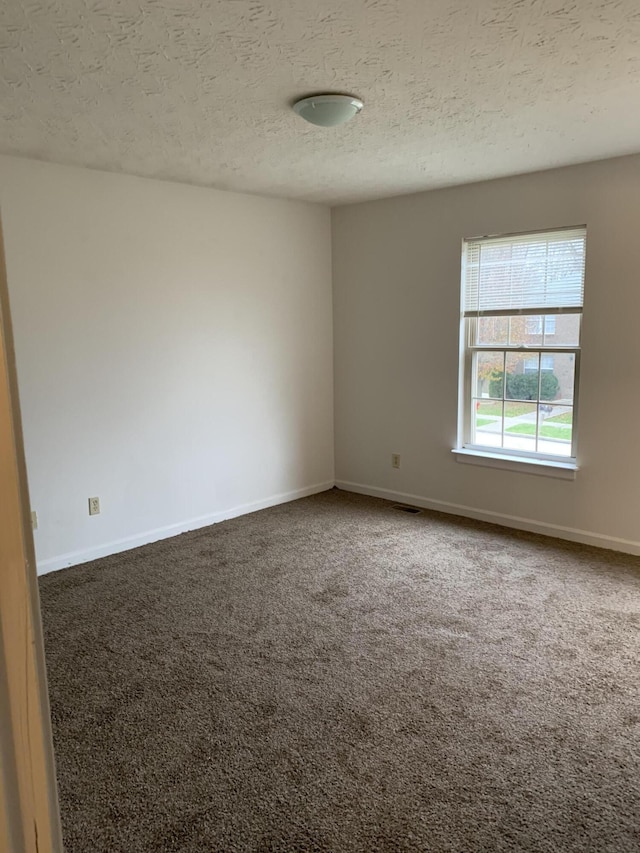 empty room with baseboards, carpet floors, and a textured ceiling