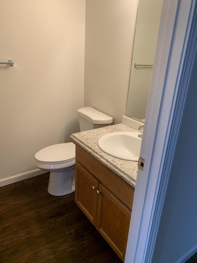 bathroom featuring vanity, toilet, wood finished floors, and baseboards