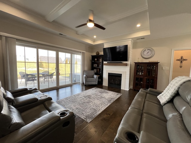 living area featuring visible vents, ornamental molding, a fireplace, ceiling fan, and dark wood-style flooring