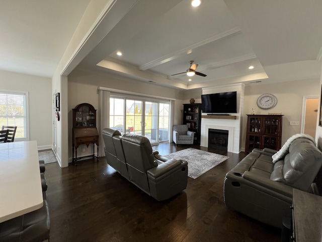 living room with a ceiling fan, dark wood finished floors, recessed lighting, a raised ceiling, and a large fireplace