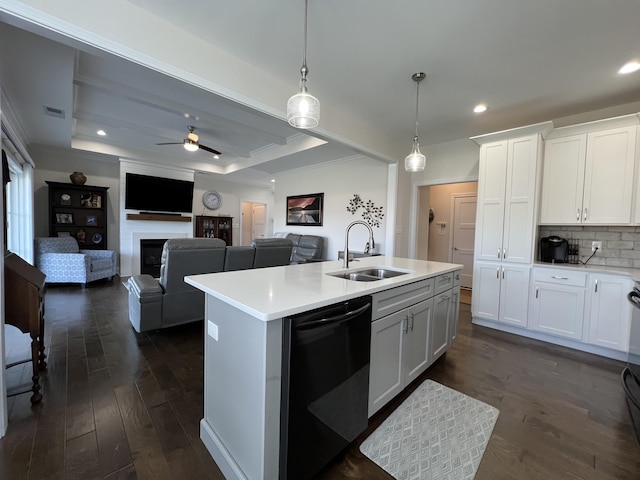 kitchen featuring a tray ceiling, dark wood finished floors, a fireplace, light countertops, and dishwasher