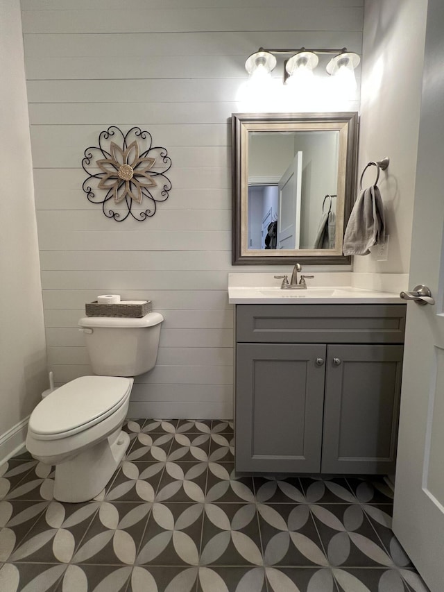 half bath with tile patterned floors, toilet, and vanity